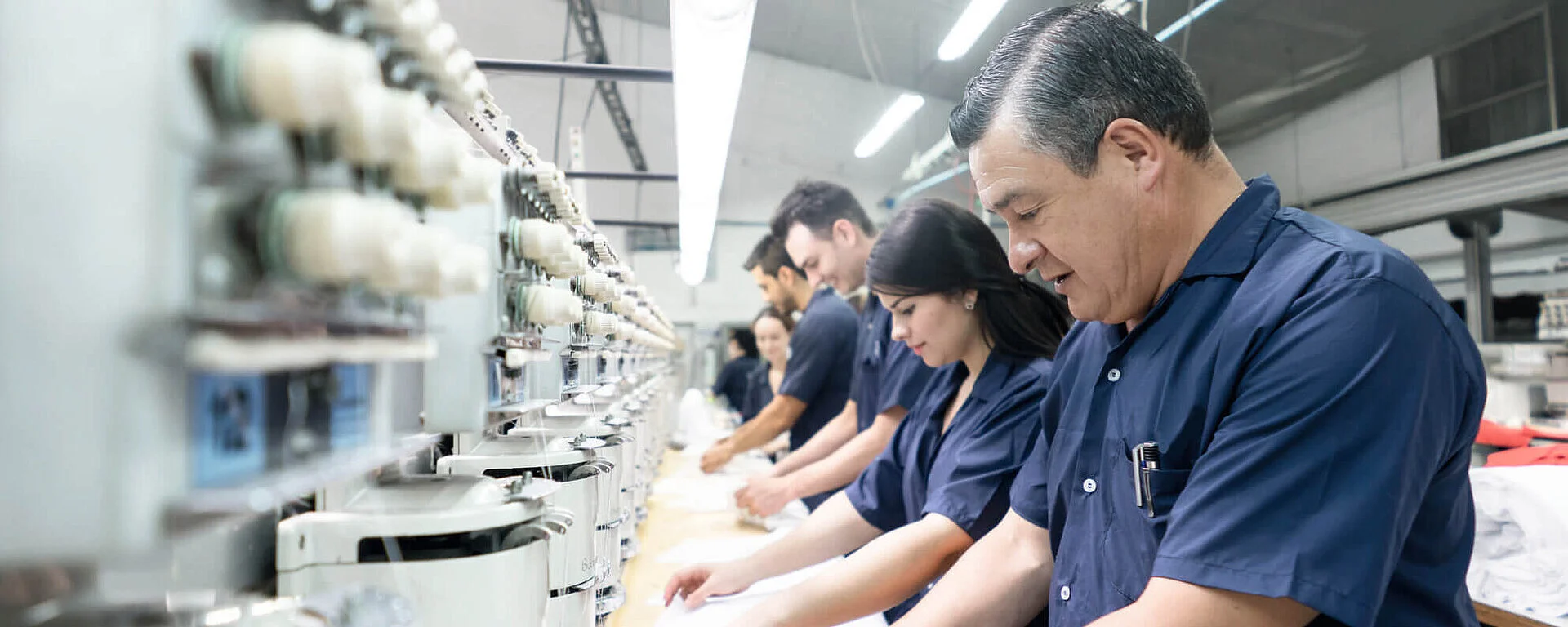 Workers in blue uniforms operating sewing machines in a textile factory
