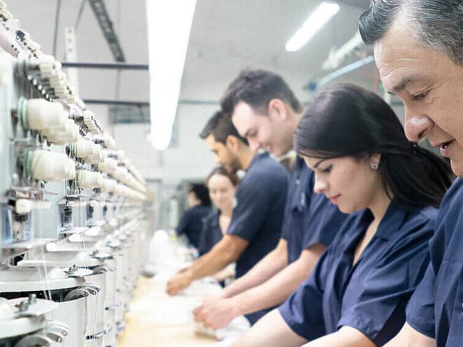 Workers in blue uniforms operating sewing machines in a textile factory