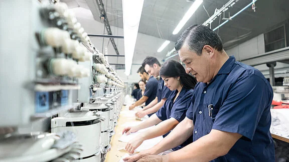 Workers in blue uniforms operating sewing machines in a textile factory
