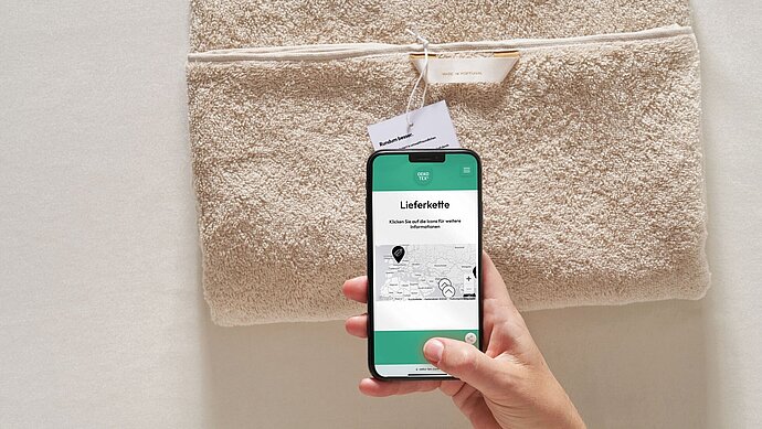 Hand mit einem Smartphone, auf dem Screen sieht man Informationen über die MADE IN GREEN Zertifizierung